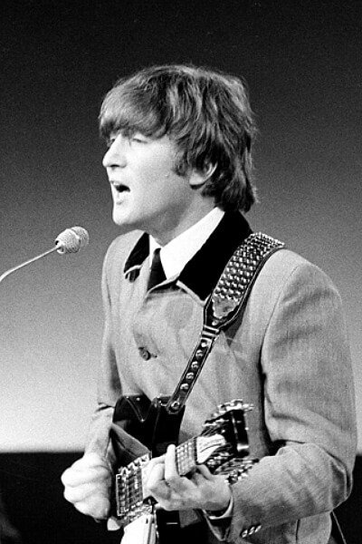 John Lennon singing and playing guitar, likely during a Beatles performance.